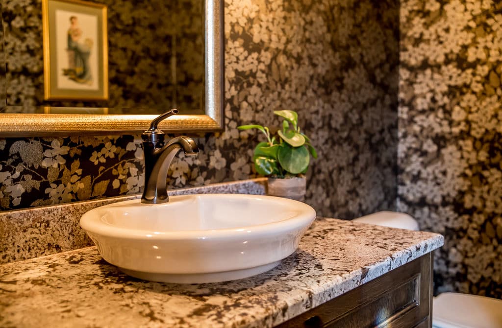 Elegant bathroom with floral wallpaper, a vintage sink, and a decorative plant.