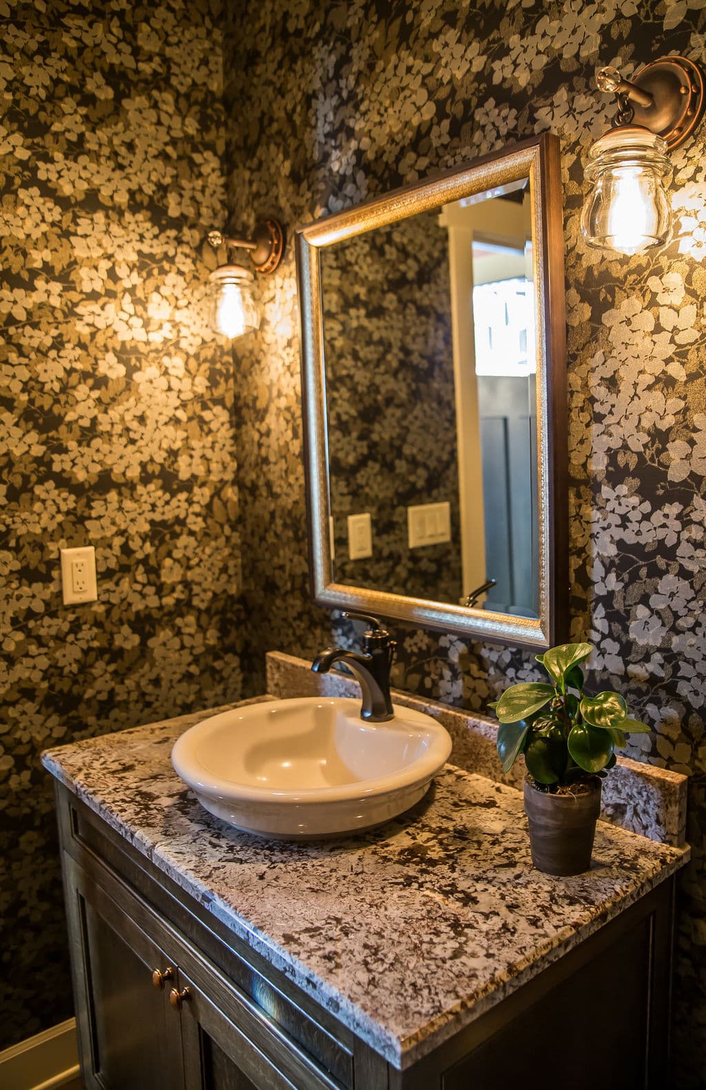 Elegant bathroom with floral wallpaper, granite countertop, and stylish basin sink.
