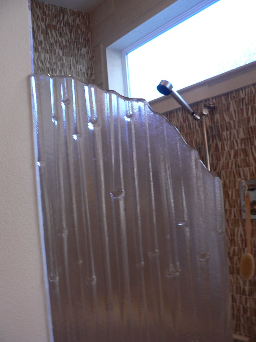 Modern shower with textured glass panel and wall-mounted showerhead in stylish bathroom.