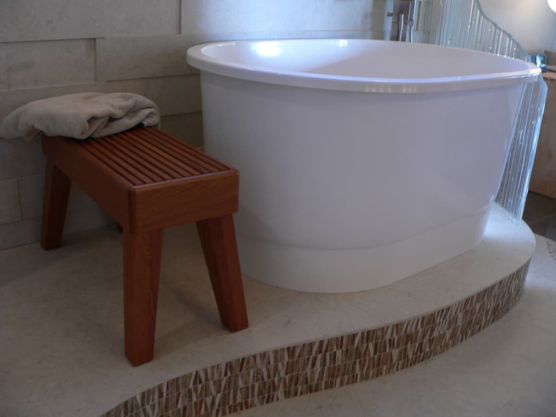Modern bathroom featuring a white freestanding bathtub and a wooden bench. Elegant design elements.