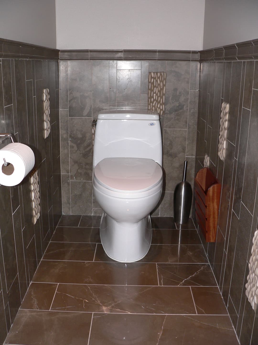 Modern bathroom with a white toilet, tiled walls, and stylish decor elements.