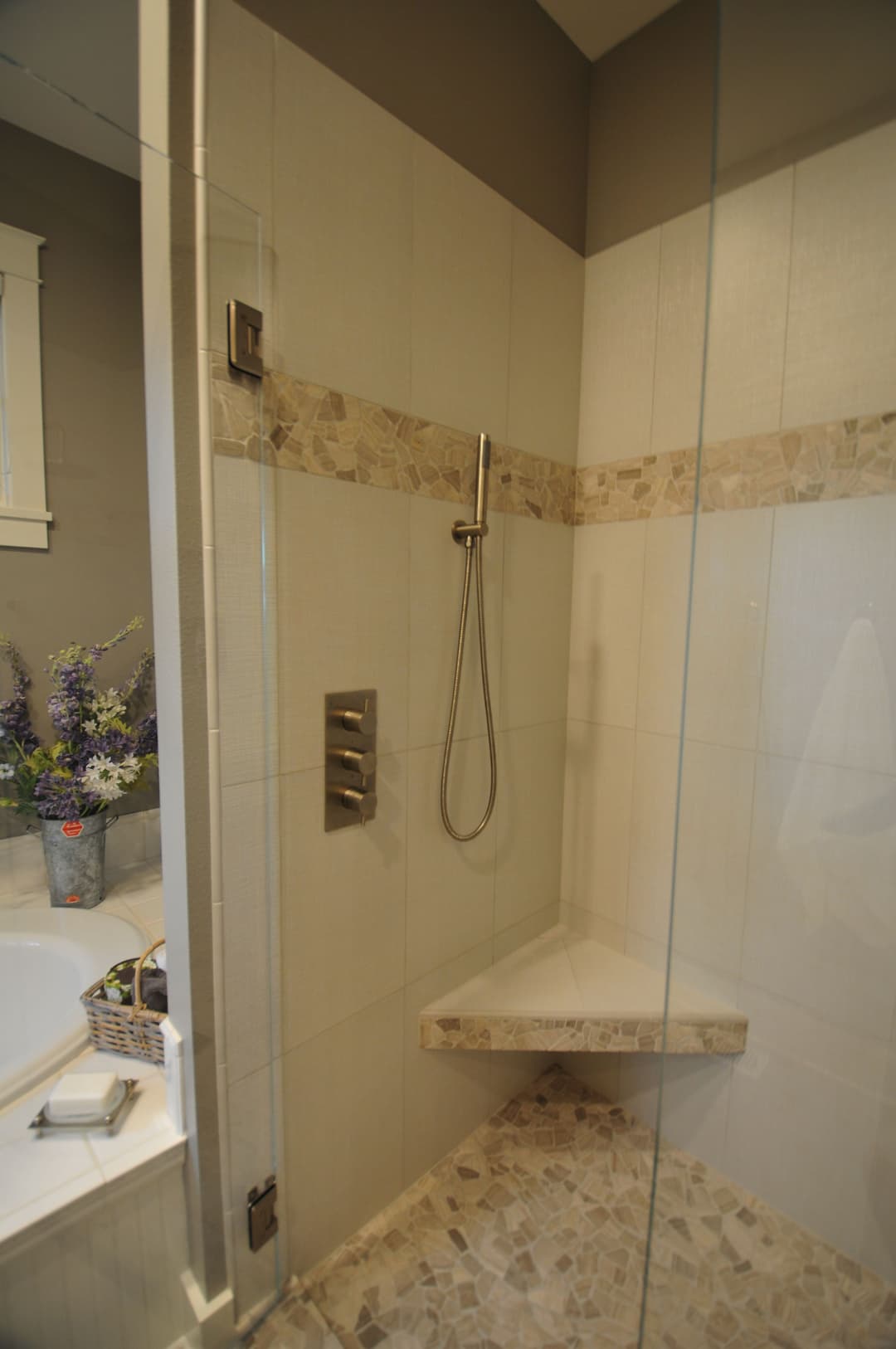 Modern walk-in shower with tiled walls, corner bench, and elegant fixtures.