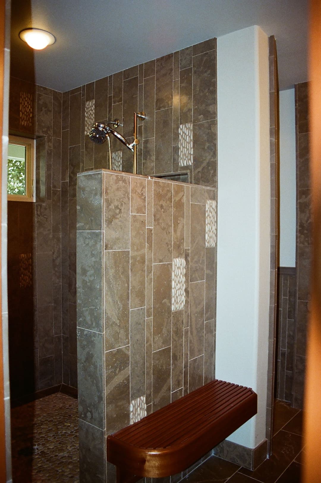 Modern shower with elegant tile design, adjustable showerhead, and wooden bench for comfort.