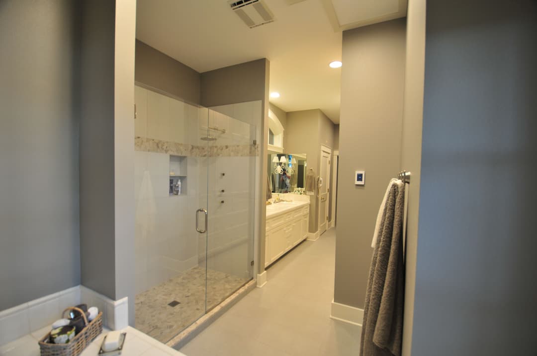 Modern bathroom interior with glass shower, dual sinks, and neutral color scheme.