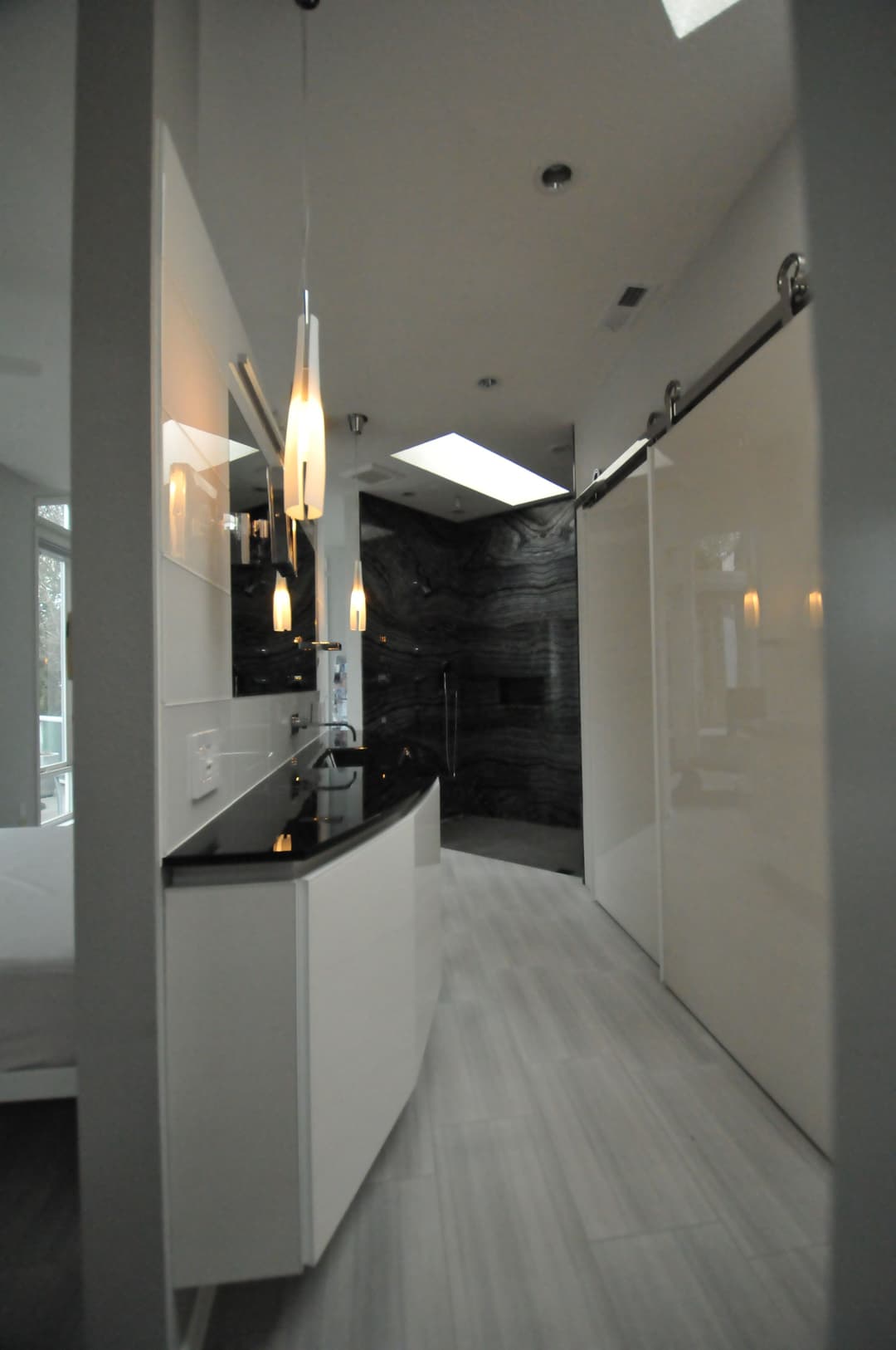 Modern bathroom with sleek design, featuring a black countertop and glass shower.