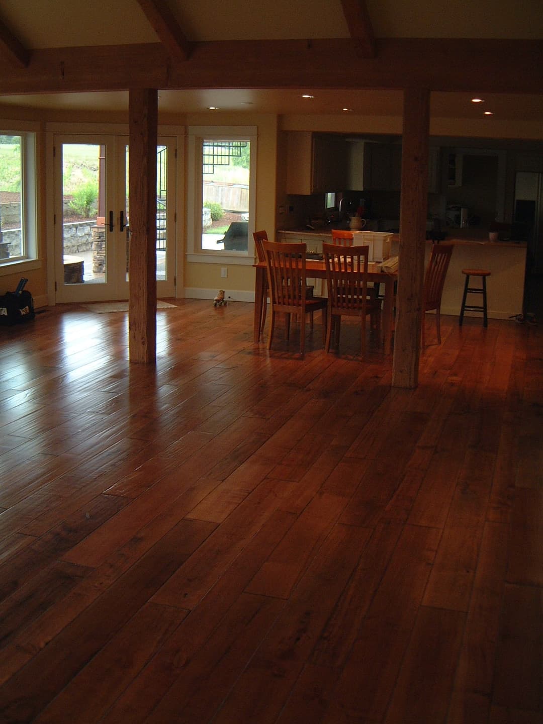 Spacious living area with hardwood floors, large windows, and dining setup.