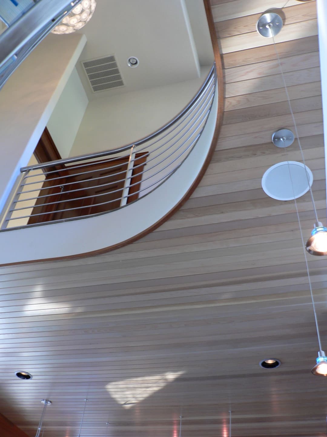 Curved wooden staircase with modern railings and ceiling lights in a stylish interior.