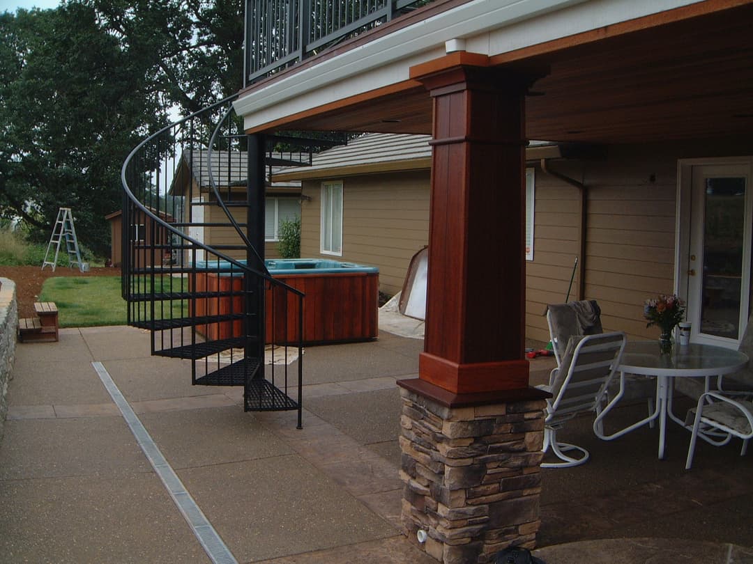 Spiral staircase leading to a deck with a hot tub and outdoor seating area.