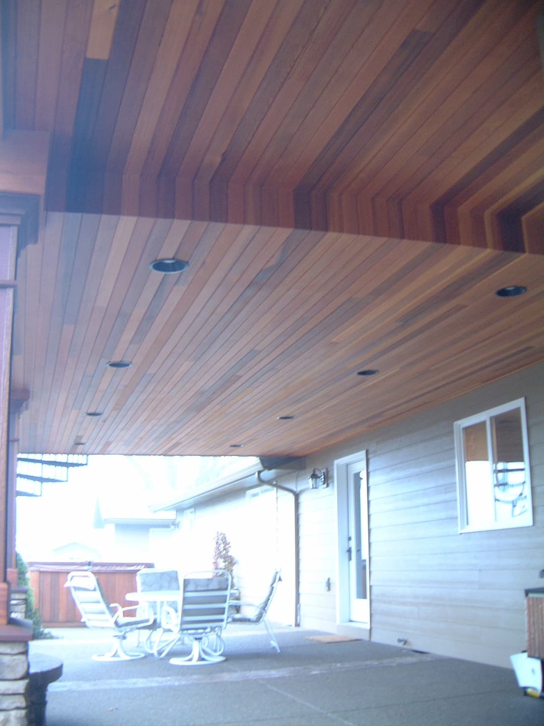 Wooden ceiling with recessed lighting over patio dining area, enhancing outdoor living space.