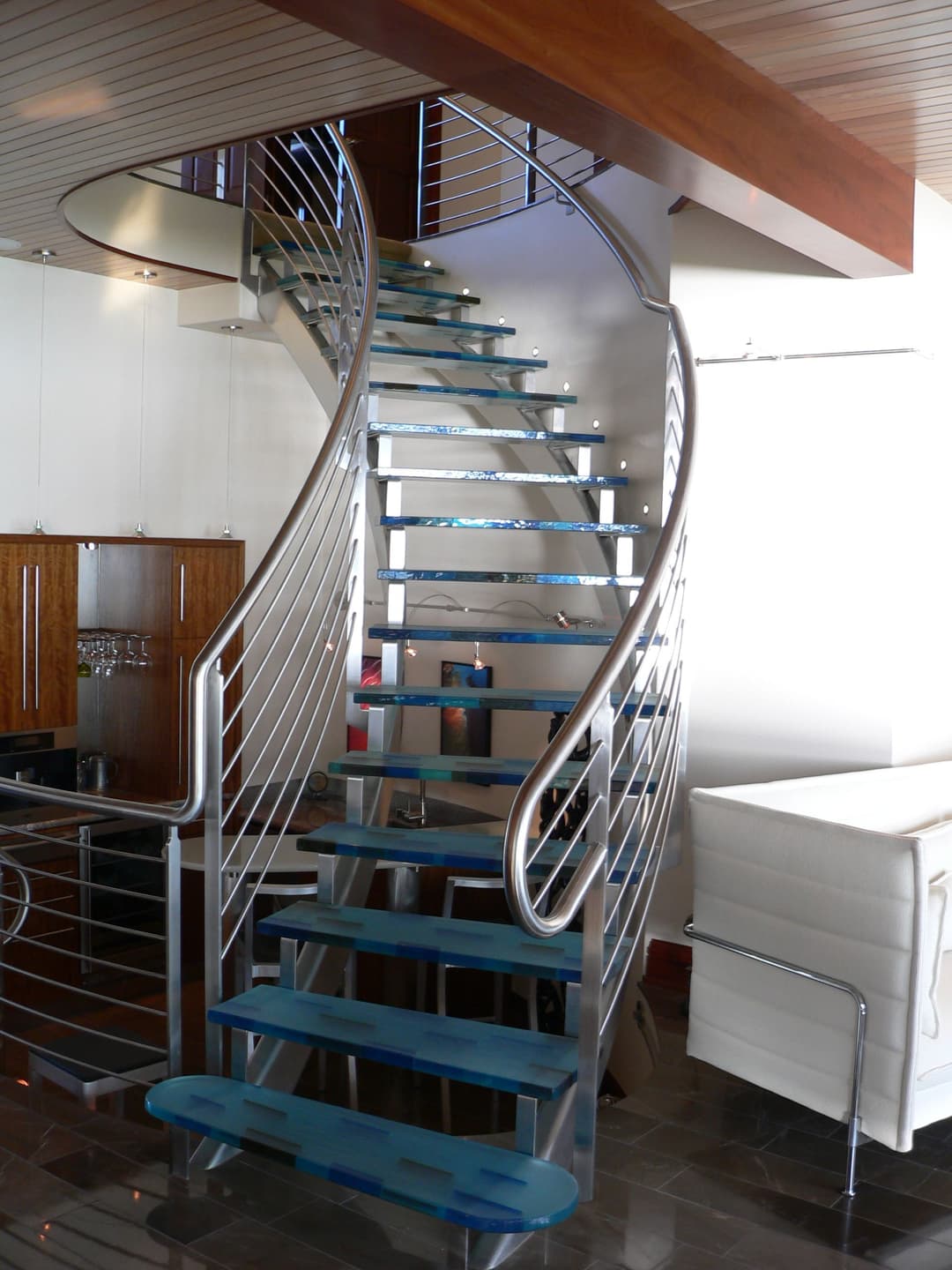 Modern spiral staircase with glass steps and metal railings in a contemporary interior design.