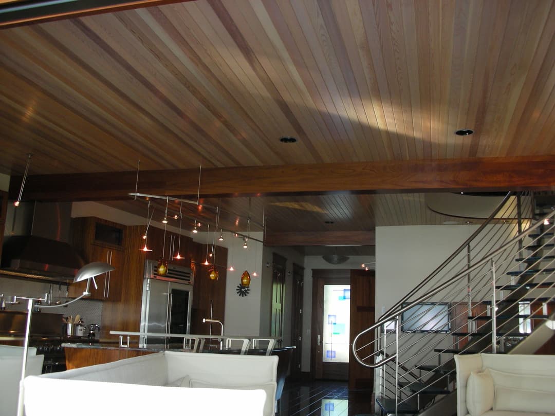 Modern interior design showcasing a wood-paneled ceiling, sleek kitchen, and elegant staircase.
