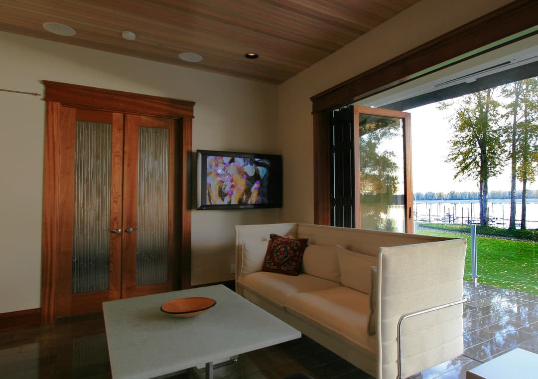 Modern living room with wooden accents, large windows, and scenic lake view.