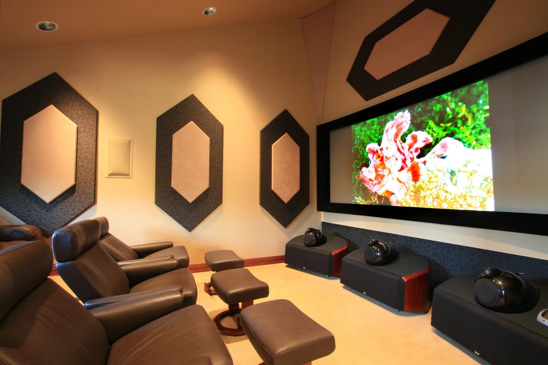 Home theater with comfortable leather seating, large screen, and acoustic wall design.