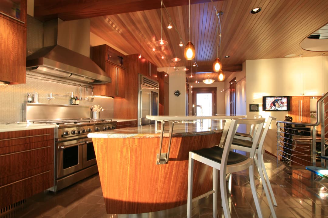 Modern kitchen with wooden cabinets, stainless steel appliances, and sleek island seating.