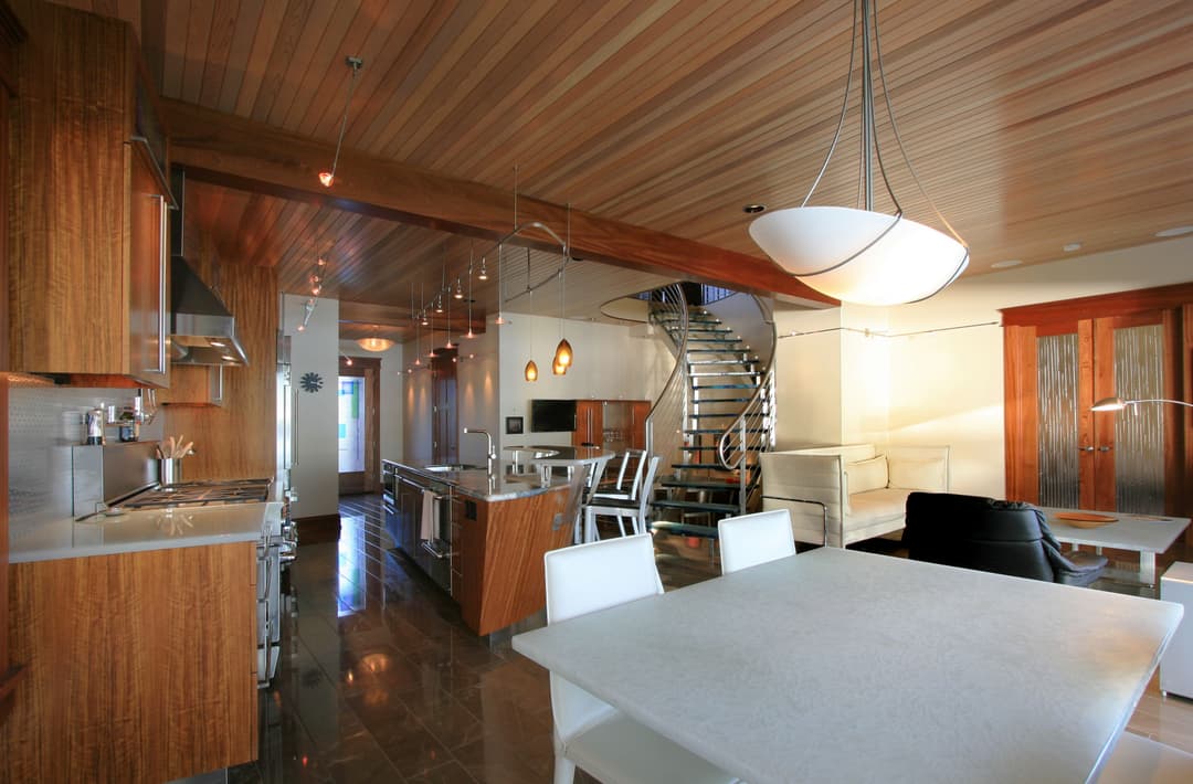 Modern kitchen with wooden accents, stainless steel appliances, and spiral staircase.