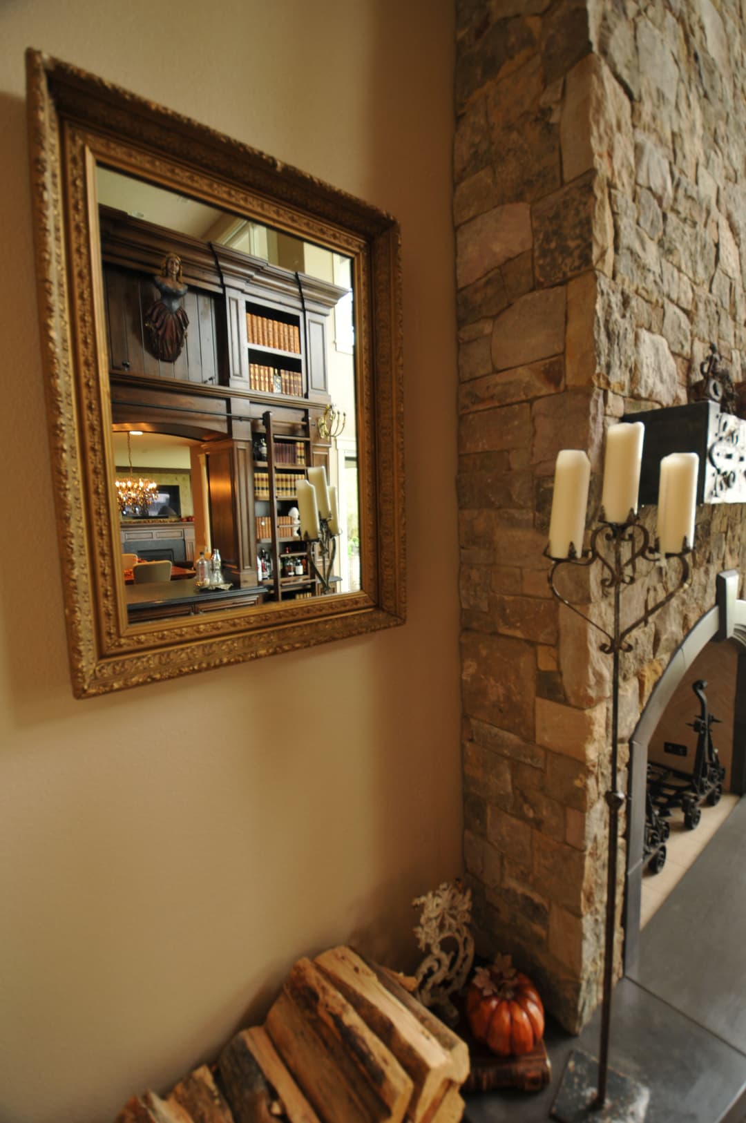 Elegant living room with stone fireplace, ornate mirror, and cozy decor accents.