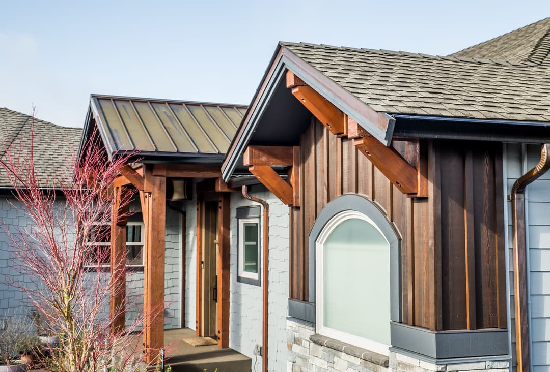 Modern home exterior featuring wooden accents, stone details, and a stylish roof design.