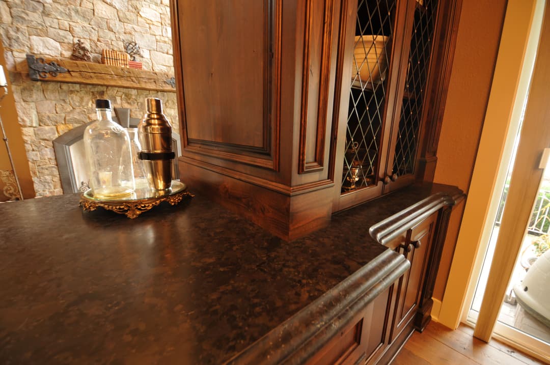 Elegant wooden cabinet with glass doors, marble countertop, and barware arranged on a tray.