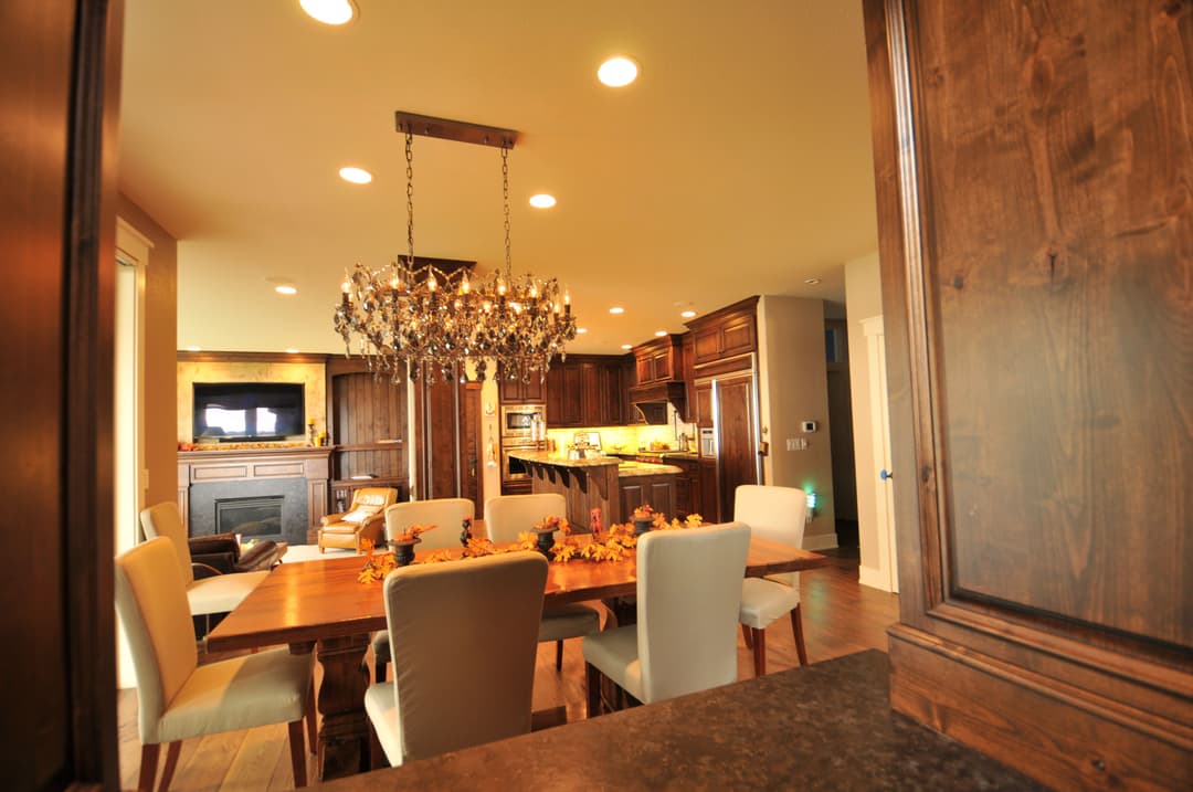 Modern kitchen with wooden cabinetry, a dining table, and a chandelier, decorated with autumn leaves.