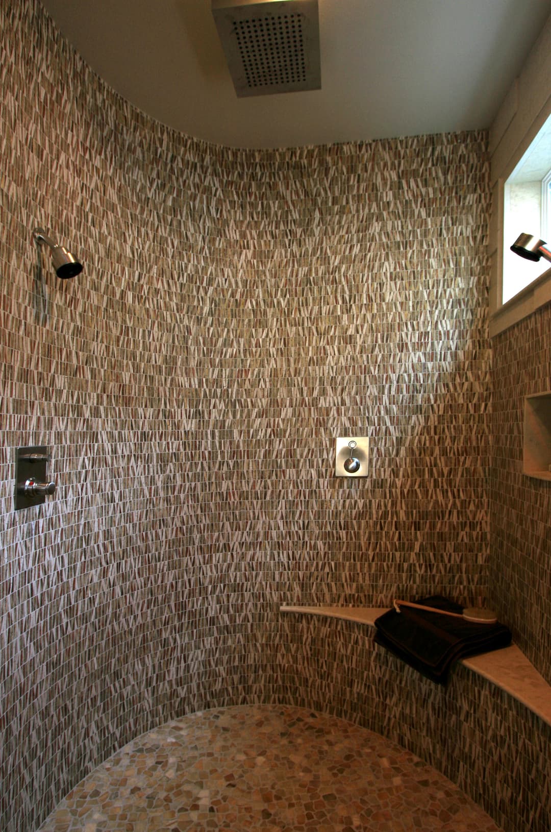 Modern shower design with textured stone walls and a stone floor, featuring ample lighting.