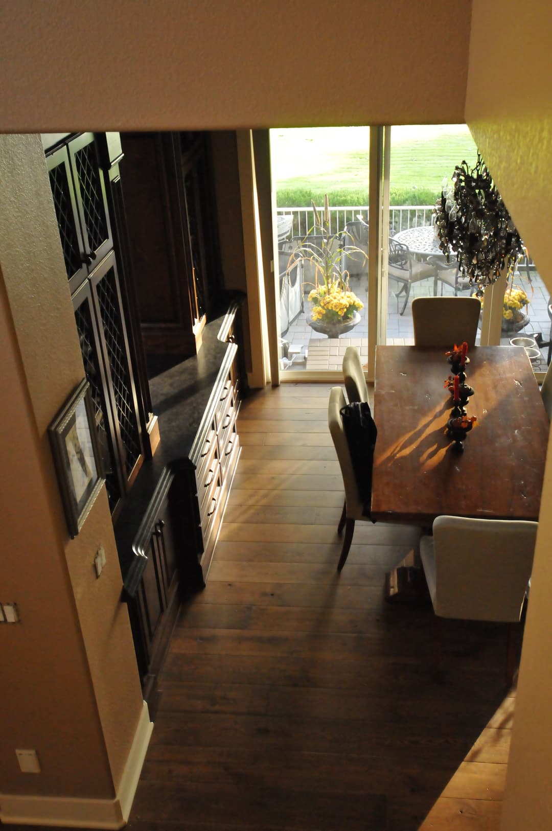 Overhead view of a modern dining area with wooden table, chairs, and sliding glass door.