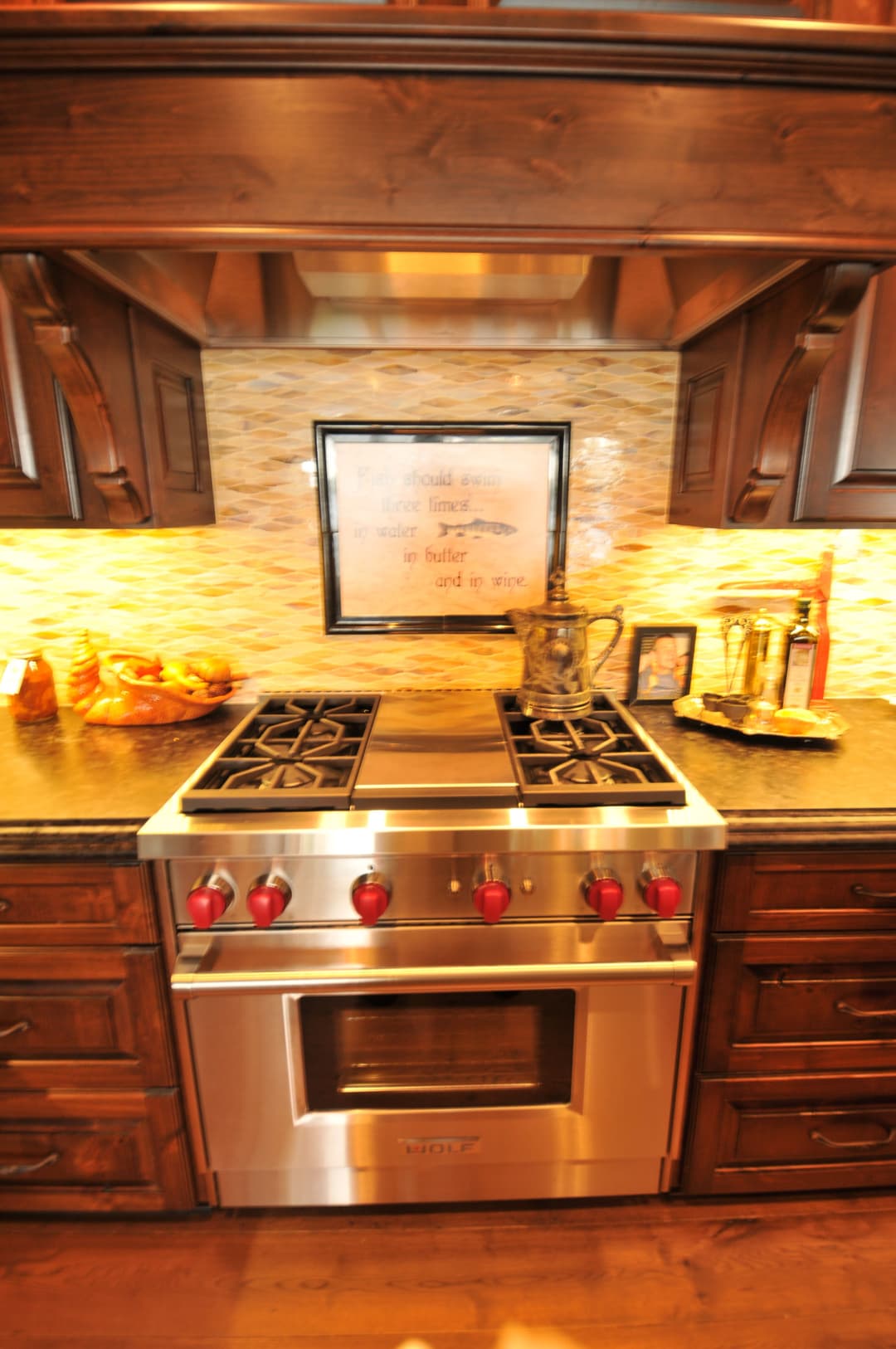 Modern kitchen with stainless steel stove, red knobs, and stylish wooden cabinetry.