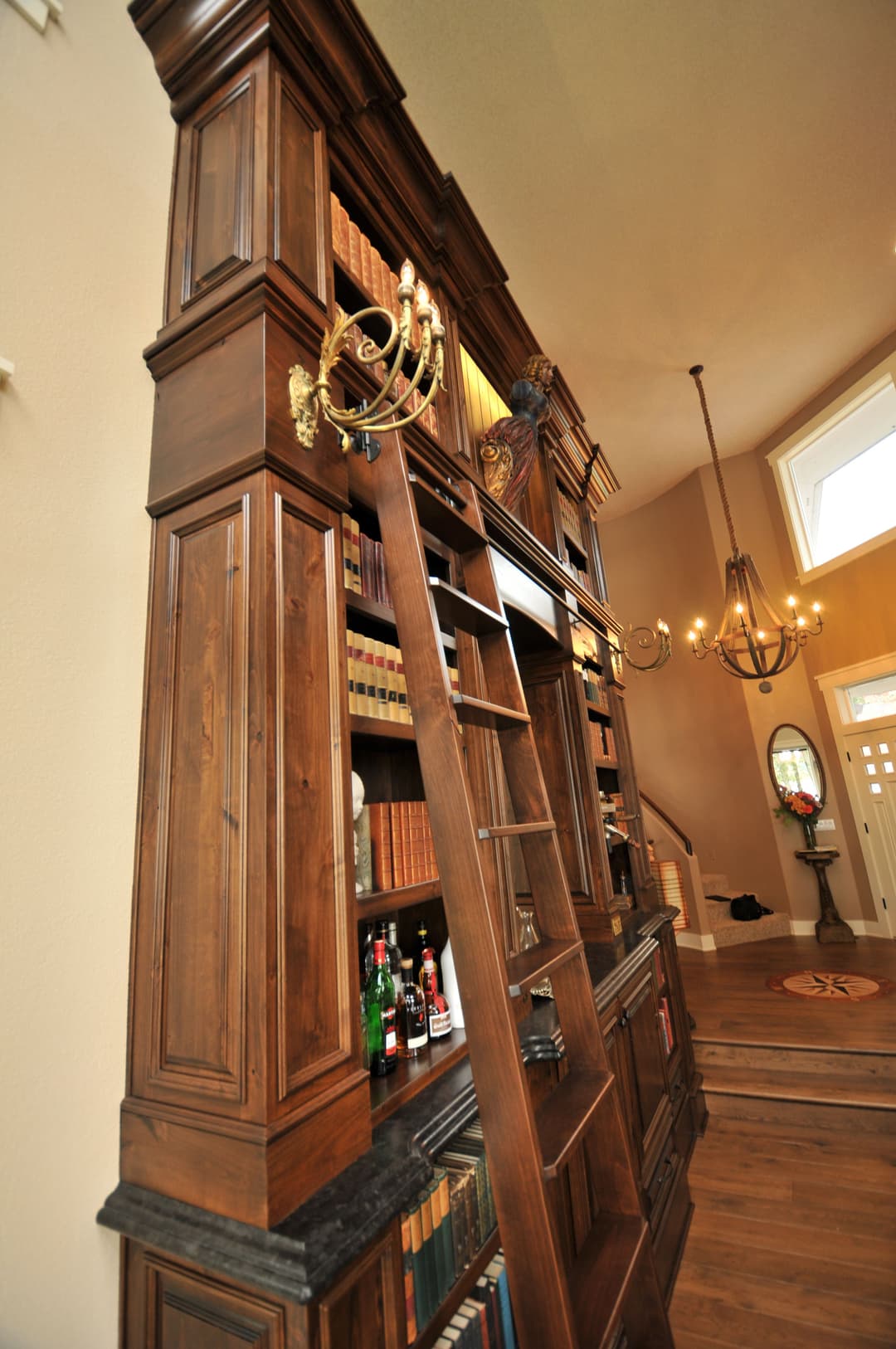 Elegant wooden bookshelf with a sliding ladder, showcasing books and decorative items in a foyer.