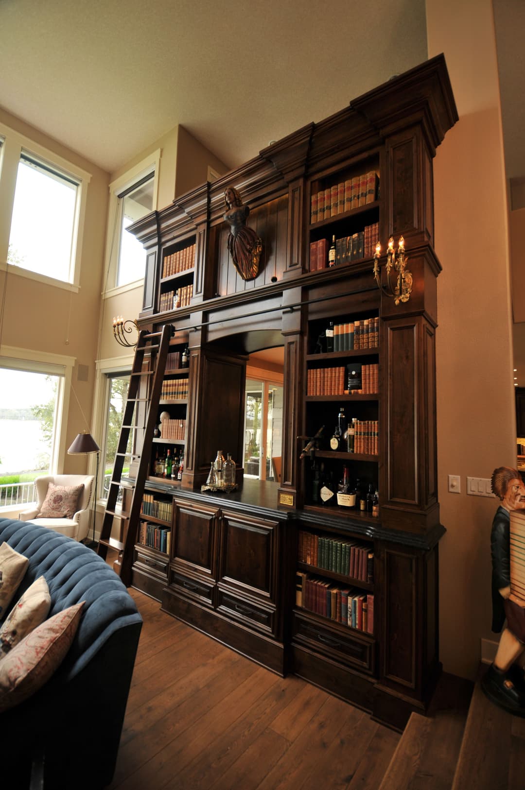 Elegant wooden bookshelf with a ladder, displaying books and decor in a stylish living room.