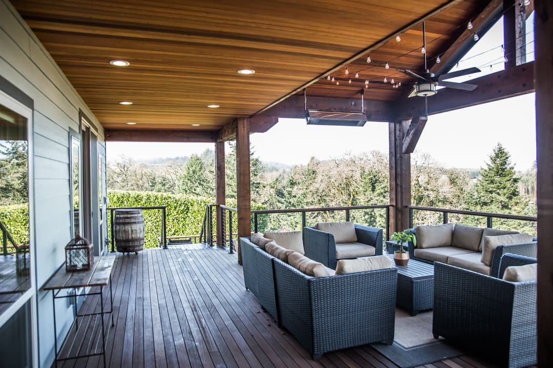 Modern outdoor patio with cozy seating, wooden ceiling, and beautiful landscape views.