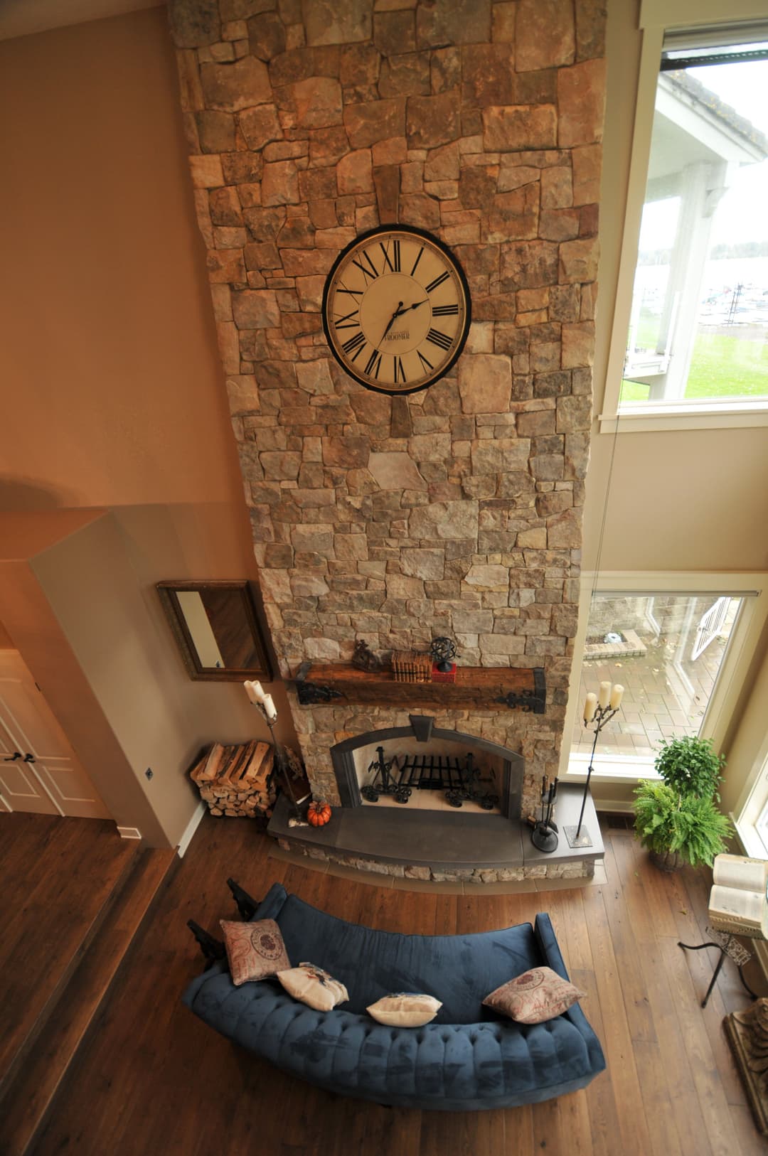 Stylish living room featuring a stone fireplace, large clock, and blue sofa with pillows.