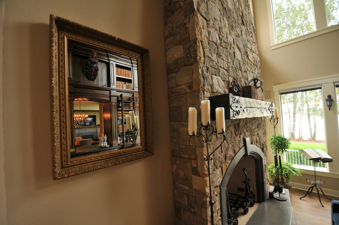 Elegant stone fireplace with ornate mirror and candle holders in cozy living room.