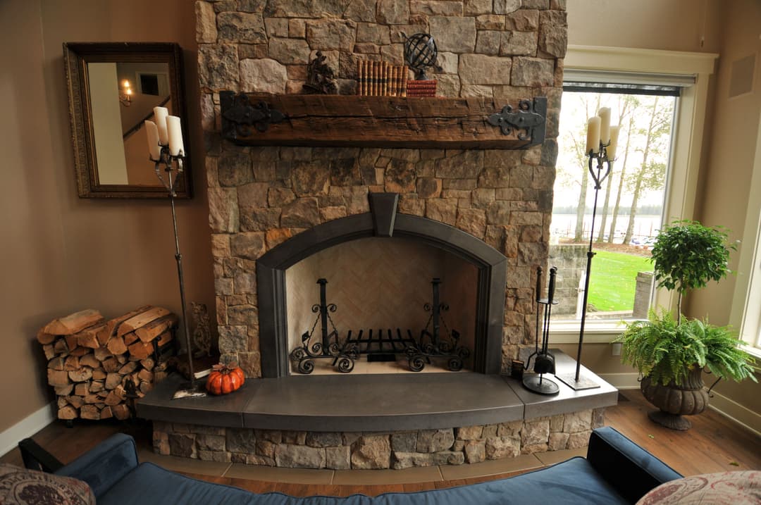 Stone fireplace with wooden mantel, decorative items, and cozy seating in a modern living room.
