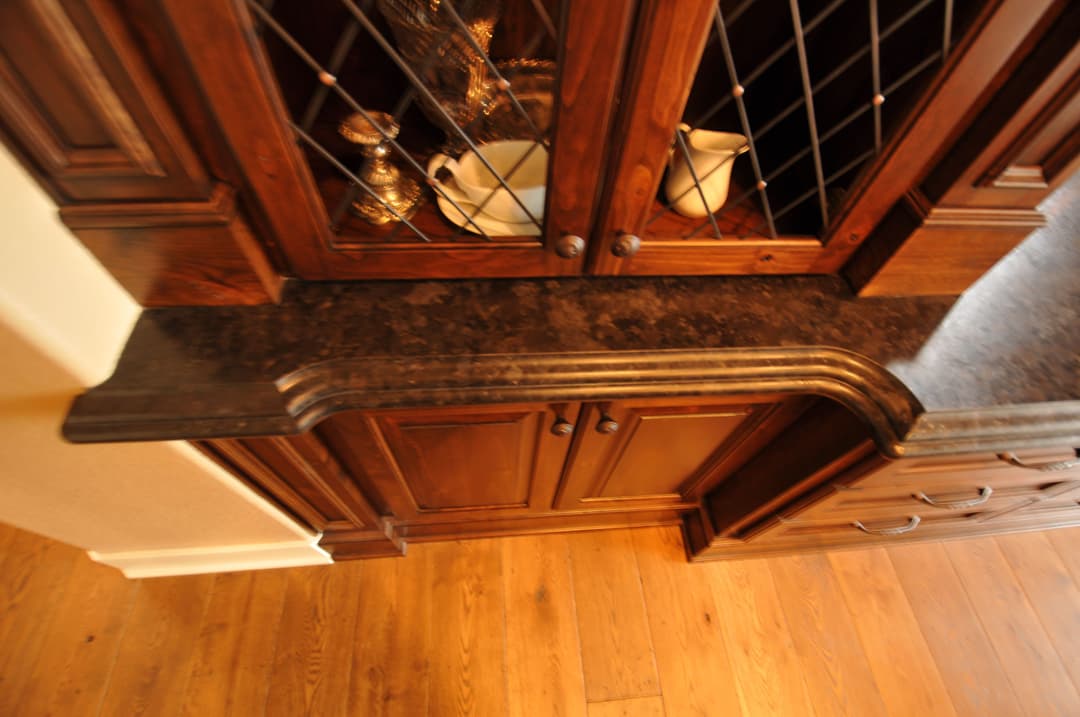 Elegant wooden cabinet with a dark granite countertop and glass door highlights.
