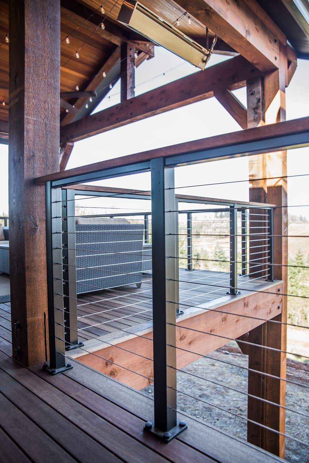 Modern balcony with cable railing and wooden deck overlooking a scenic view.