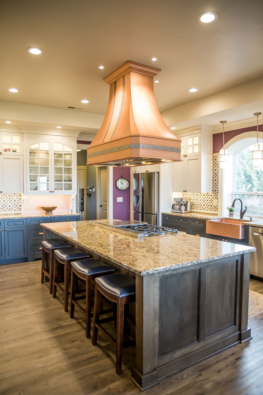 Modern kitchen featuring a large island, copper range hood, and stylish cabinetry.