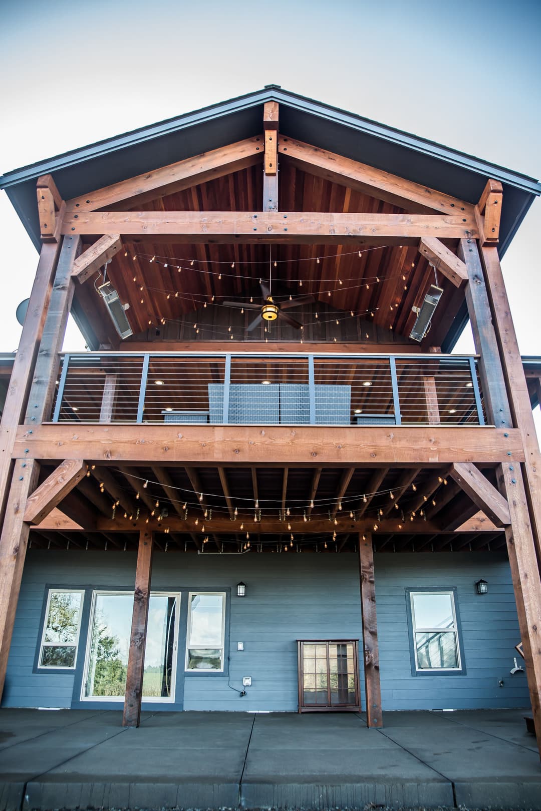 Wooden-framed modern home exterior with balcony and string lights for outdoor ambiance.