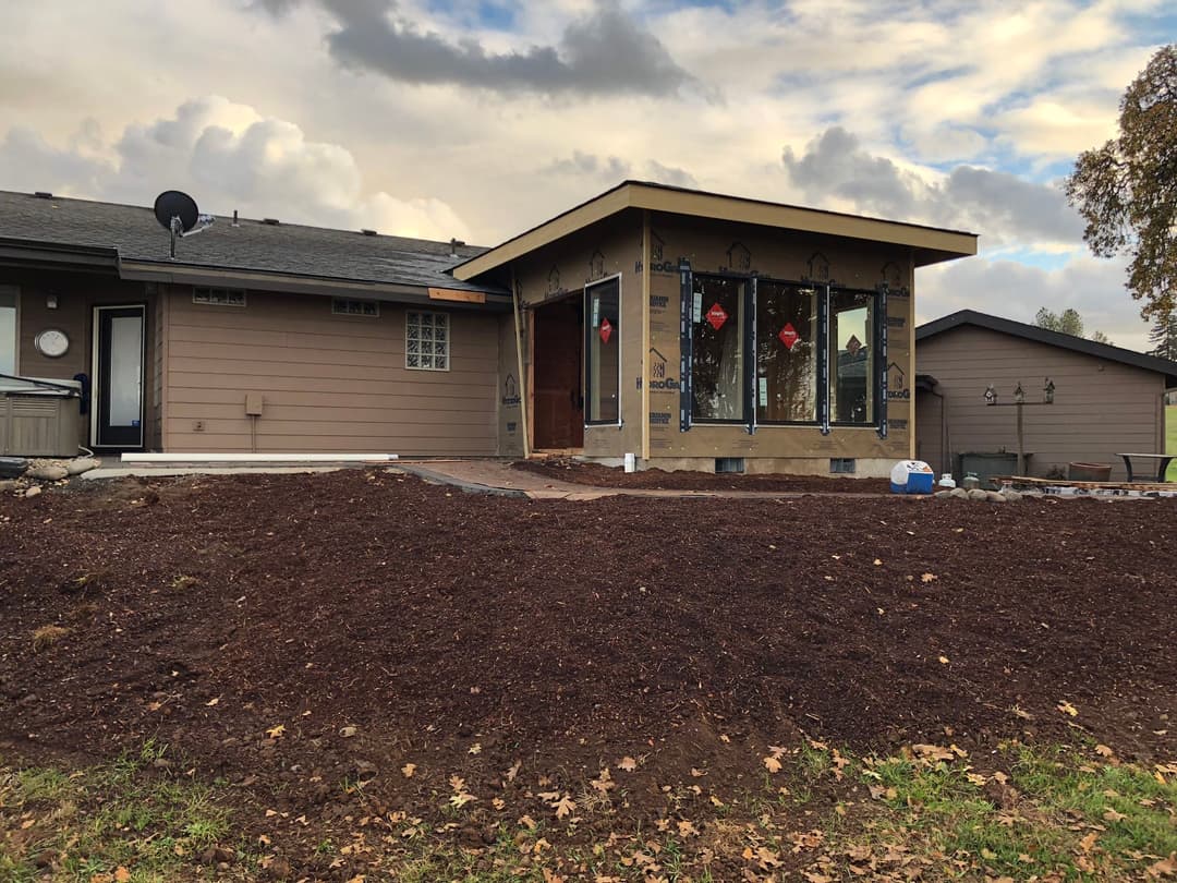 Modern home exterior with landscaped yard and cloudy sky, showcasing construction details.