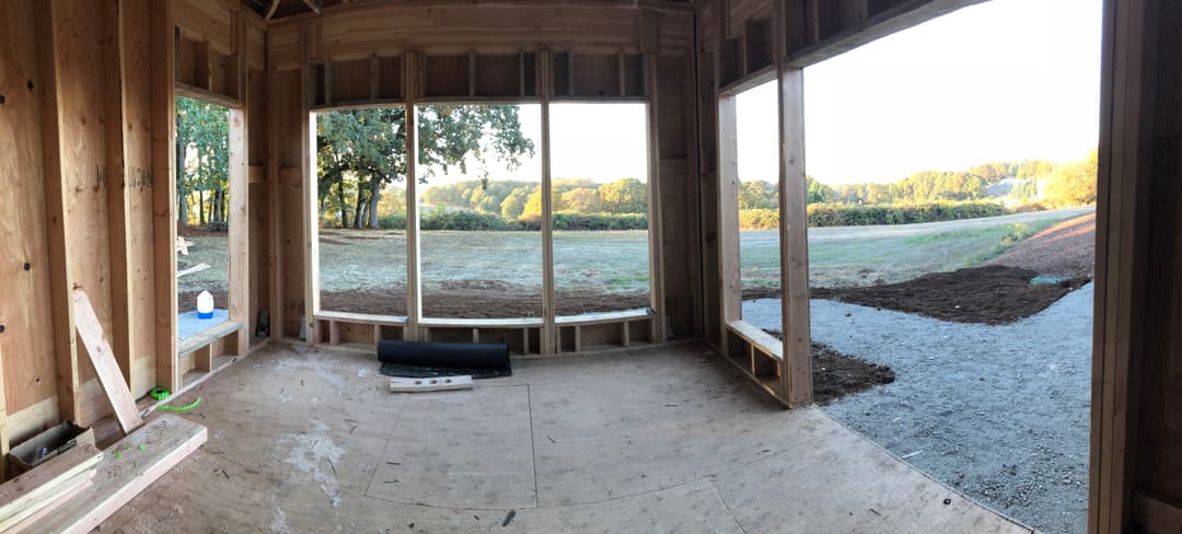 Panoramic view of a house under construction with large windows framing a scenic landscape.