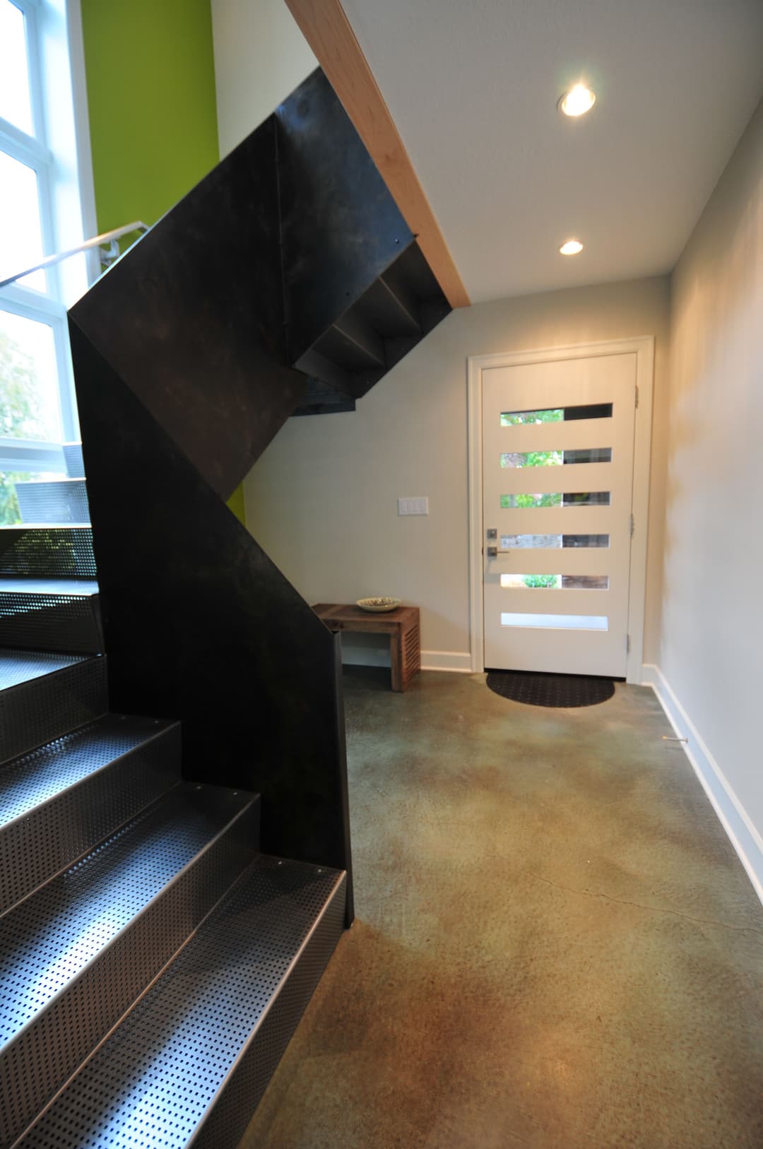 Modern staircase with metal steps leading to an entrance door in a contemporary home.
