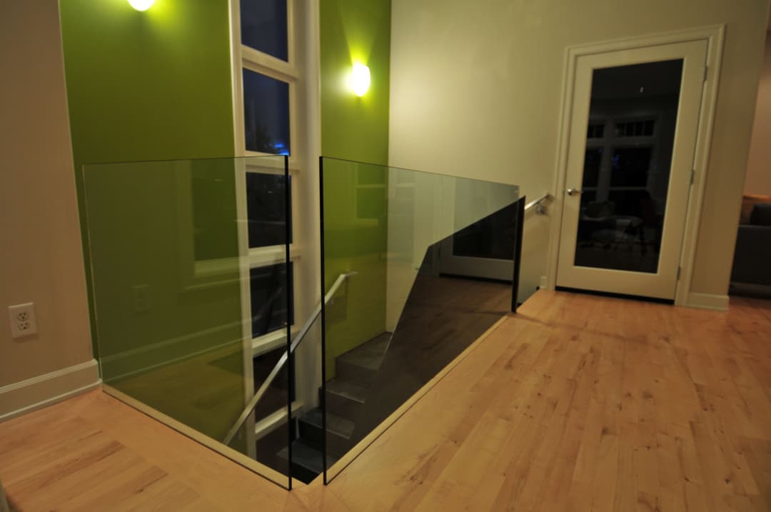 Modern interior featuring a glass railing and sleek green wall in a well-lit space.