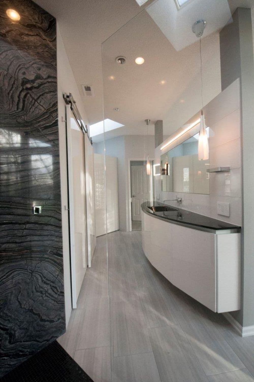 Modern bathroom with sleek design, curved vanity, and elegant lighting fixtures.
