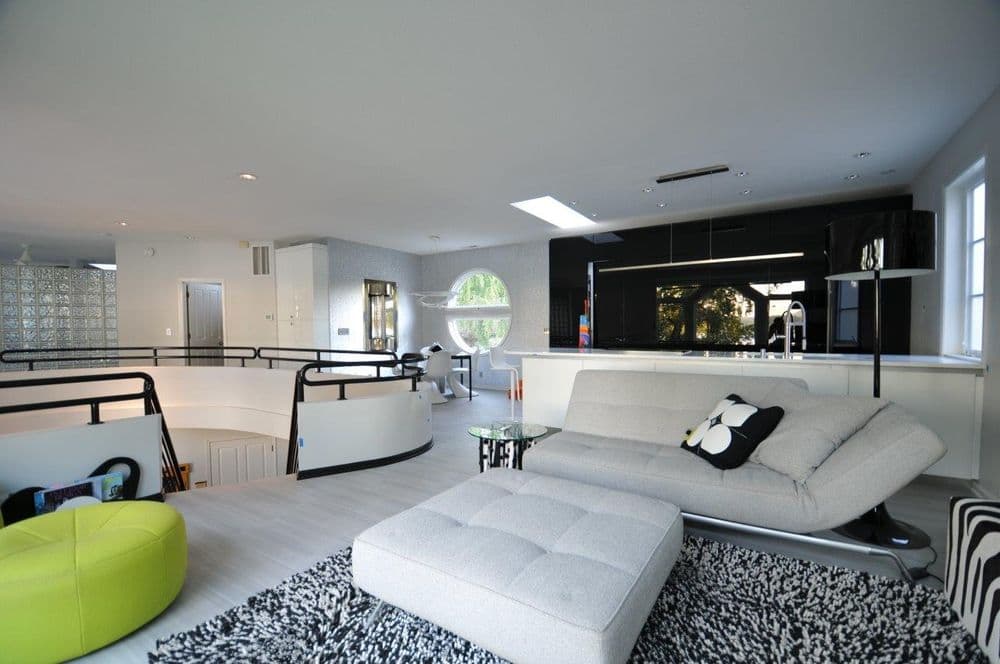 Modern open-concept living room with a sleek gray sofa, vibrant green chair, and stylish decor.