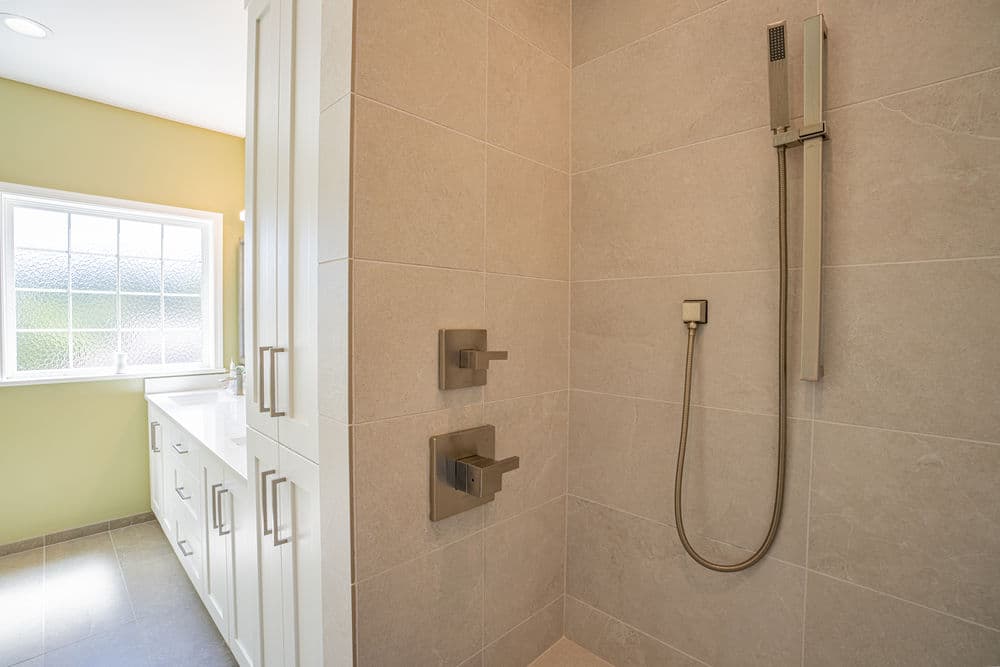 Modern bathroom shower with sleek fixtures and natural light from a nearby window.