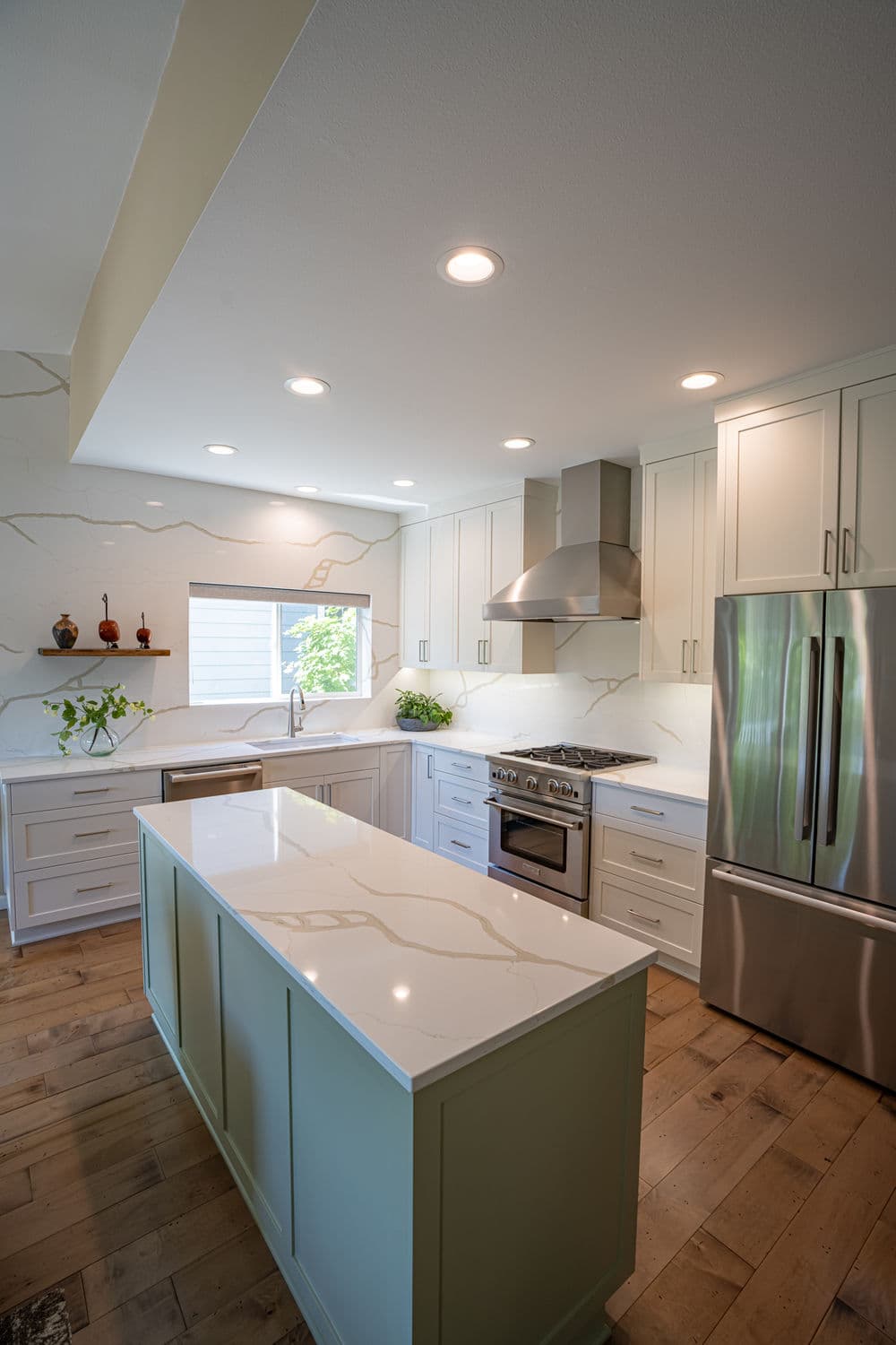Modern kitchen with light cabinetry, an island, stainless steel appliances, and natural light.