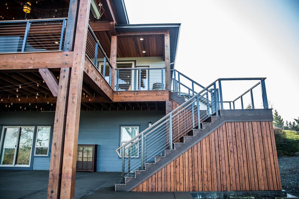Modern two-story home with wooden exterior, metal railing stairs, and balcony area.