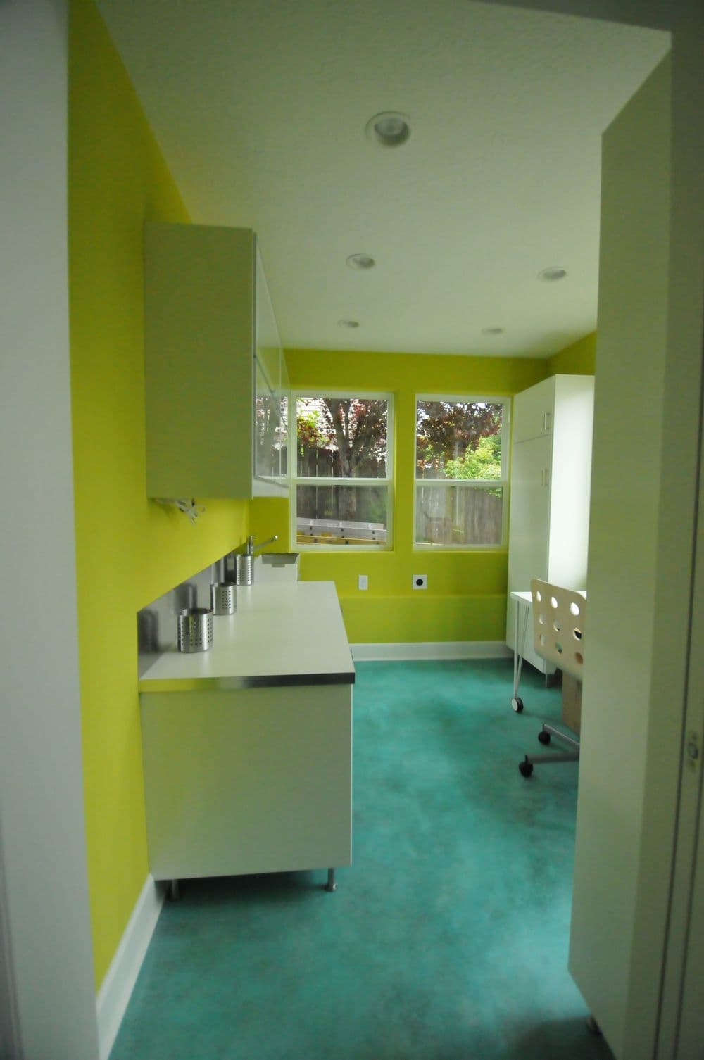 Bright modern office with green walls, large windows, and sleek white furniture.