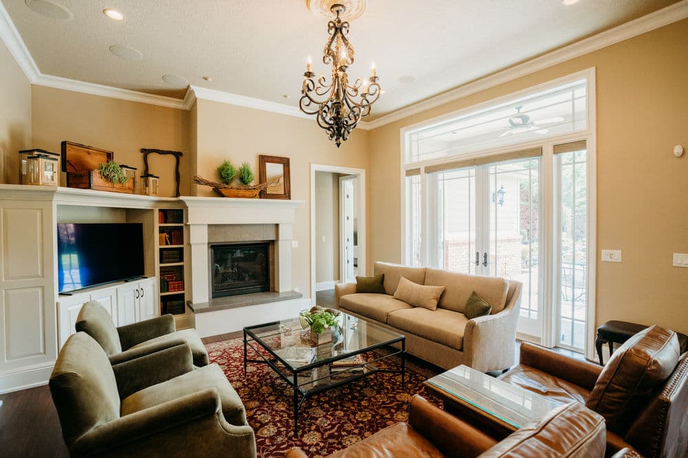 Cozy living room featuring a chandelier, fireplace, and comfortable seating with large windows.