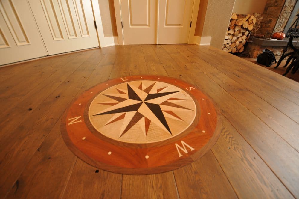 Compass rose inlaid design on hardwood floor in a cozy interior setting.