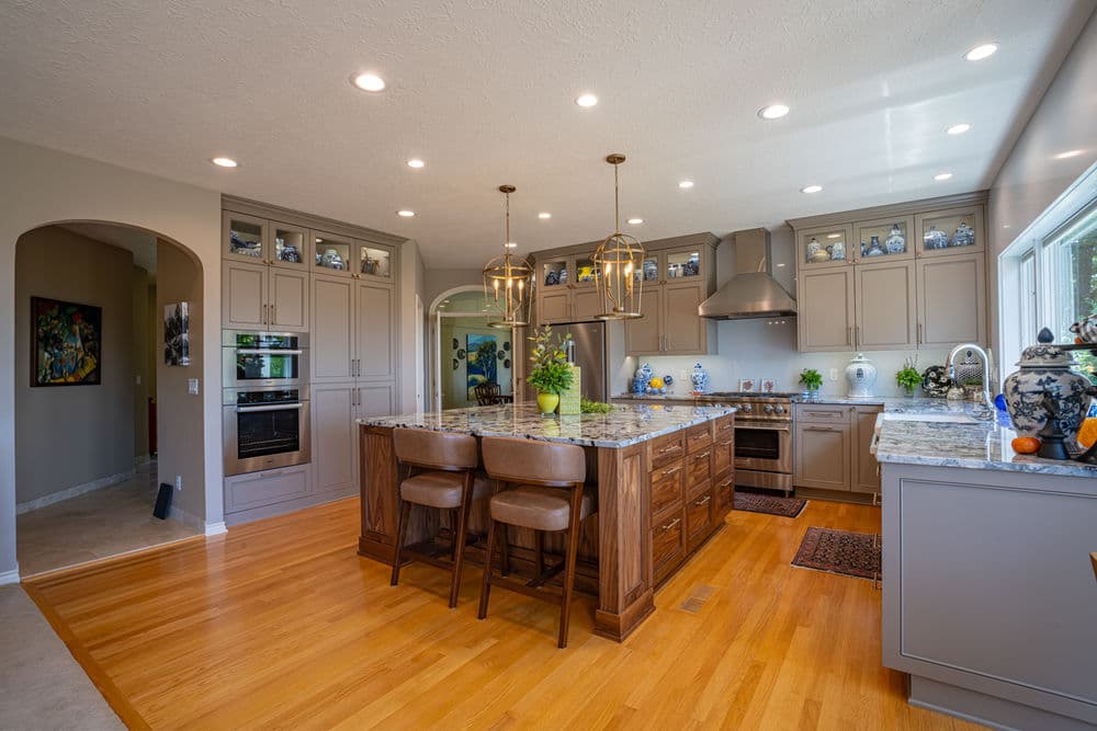 Modern kitchen with wooden island, granite countertops, and stylish pendant lighting.