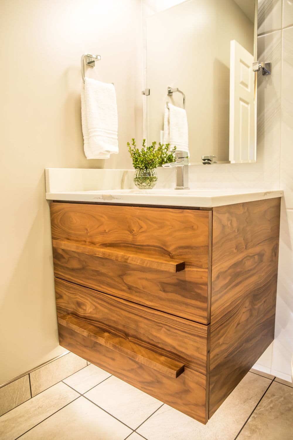Modern bathroom with wooden cabinet, white countertop, and decorative plant. Stylish and functional design.